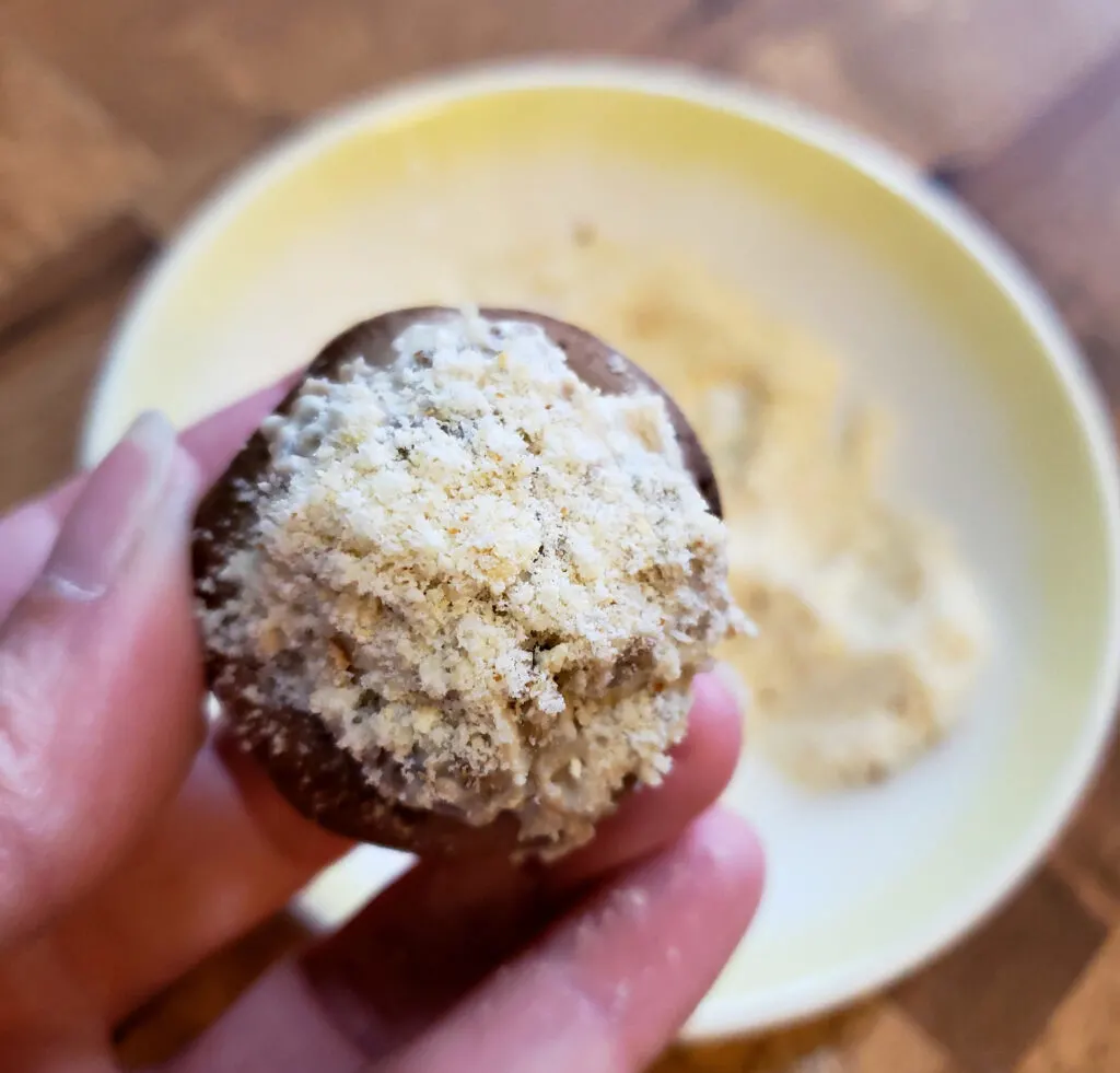 stuffed mushroom getting a crispy coating topping of parmesan and panko bread crumbs