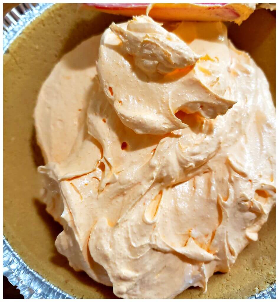 spreading orange dreamsicle chiffon pie filling in a graham cracker crust 