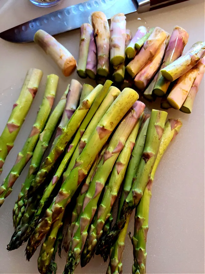This spears of asparagus cutting woody ends to prep