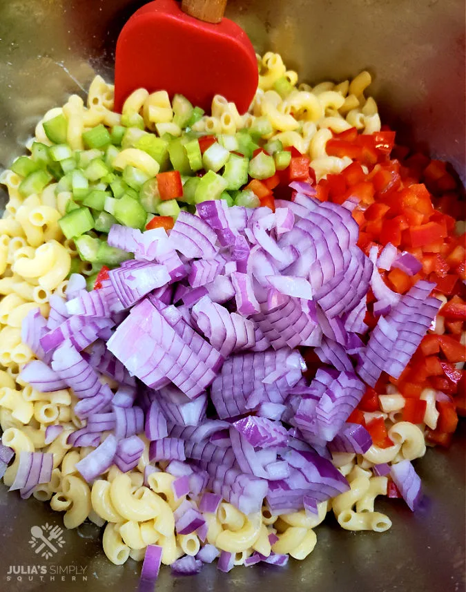 mixing bowl with ingredients to prepare a elbow macaroni pasta salad
