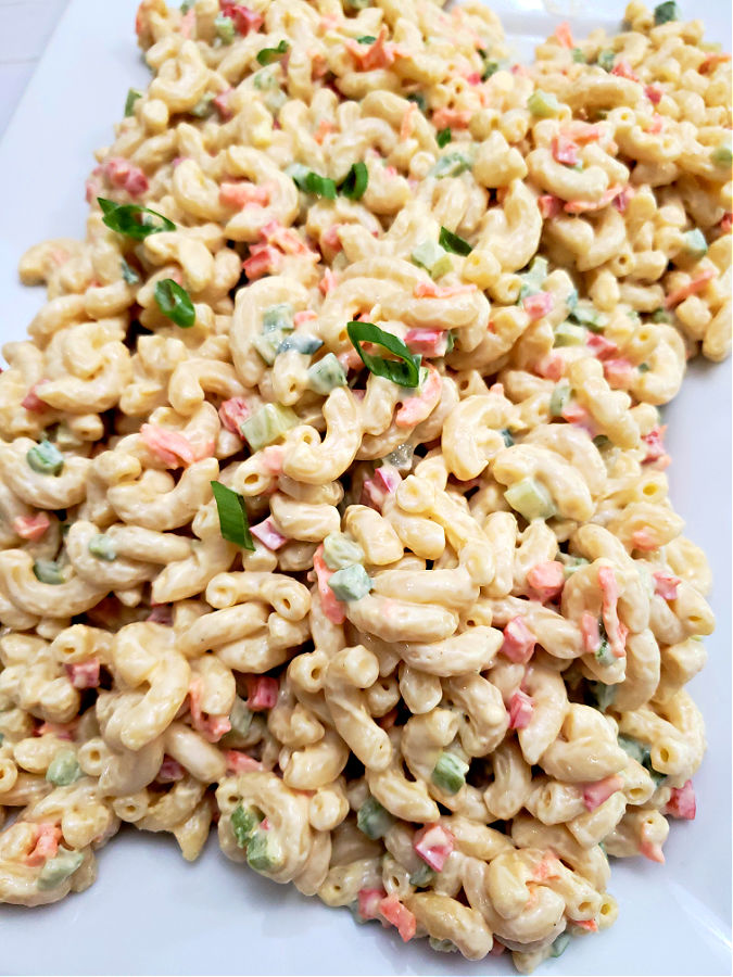 white platter with creamy old fashioned macaroni salad garnished with thin slices of green onions