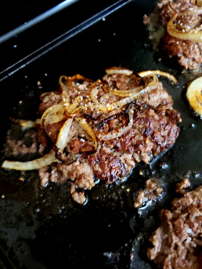 Flip meat patty to cook other side showing off crispy edges and caramelized onions for the most flavorful smash burgers