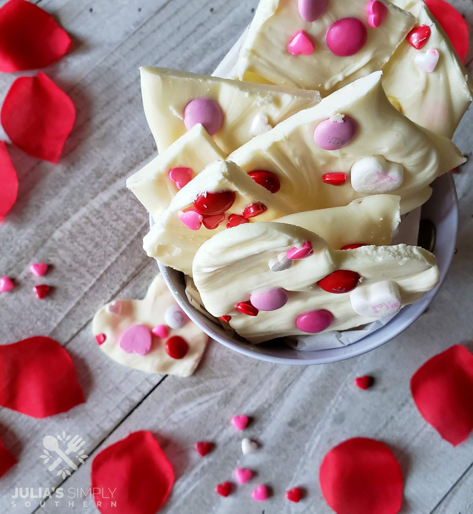 Candy bark in a Valentine's Day bucket with red rose petals