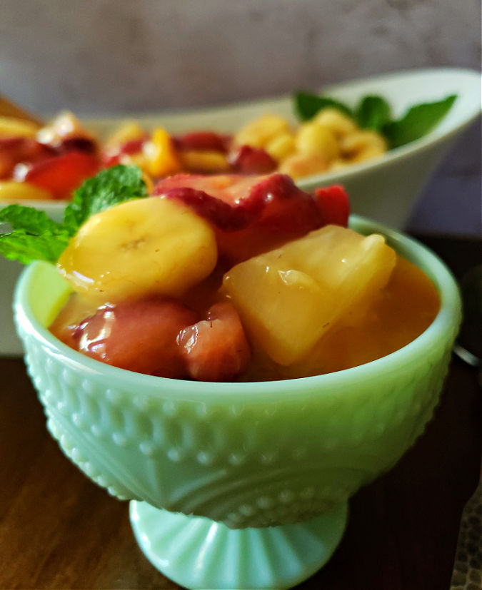 Creamy Fruit salad in a green serving dish with a garnish of mint