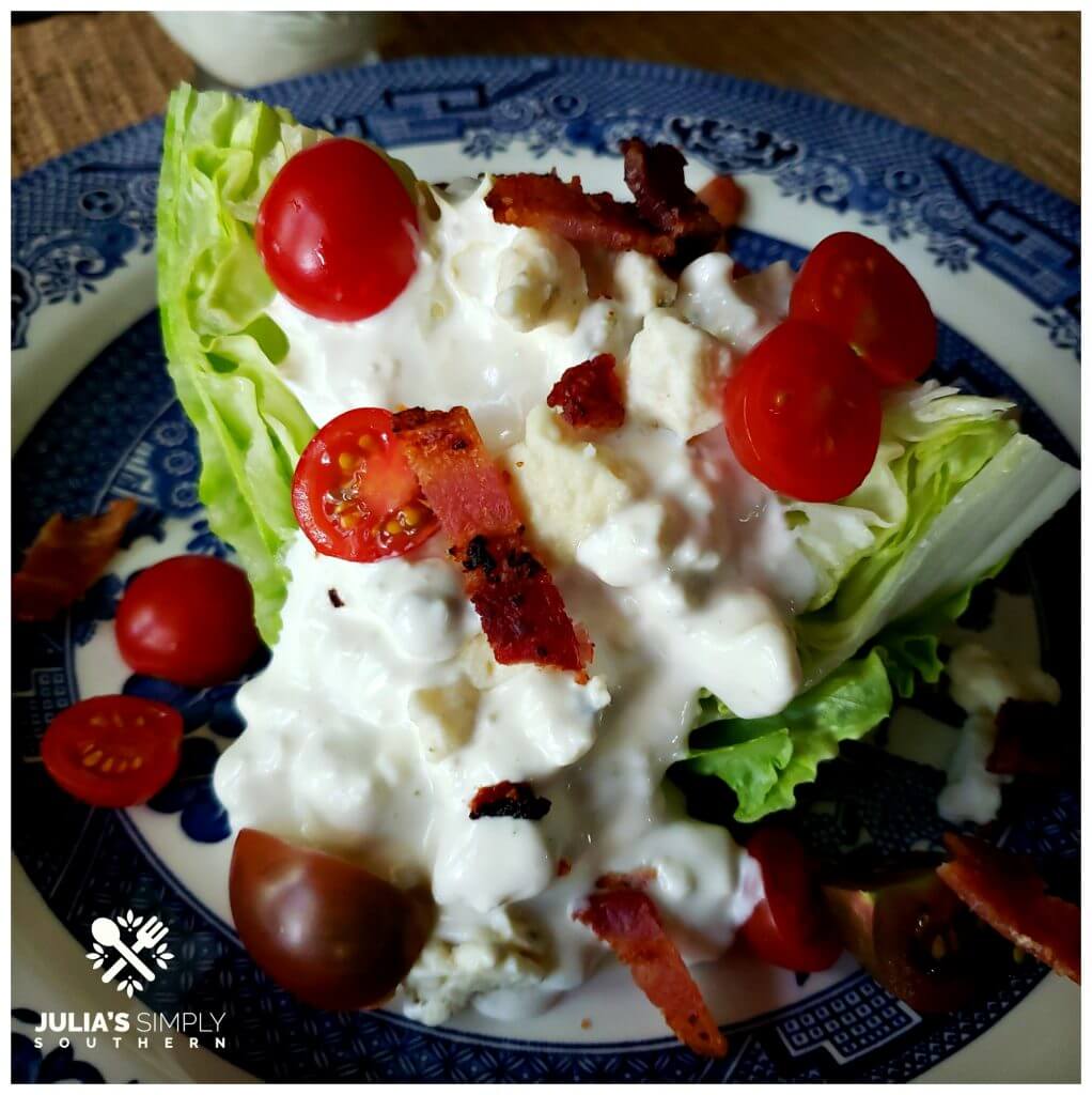 Fresh Wedge salad topped with fresh tomatoes and cooked bacon pieces with classic blue cheese dressing. Danish blue cheese
