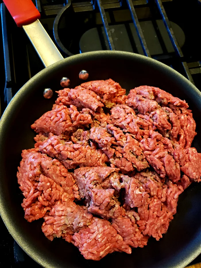 cooking minced beef in a skillet on a gas cook top