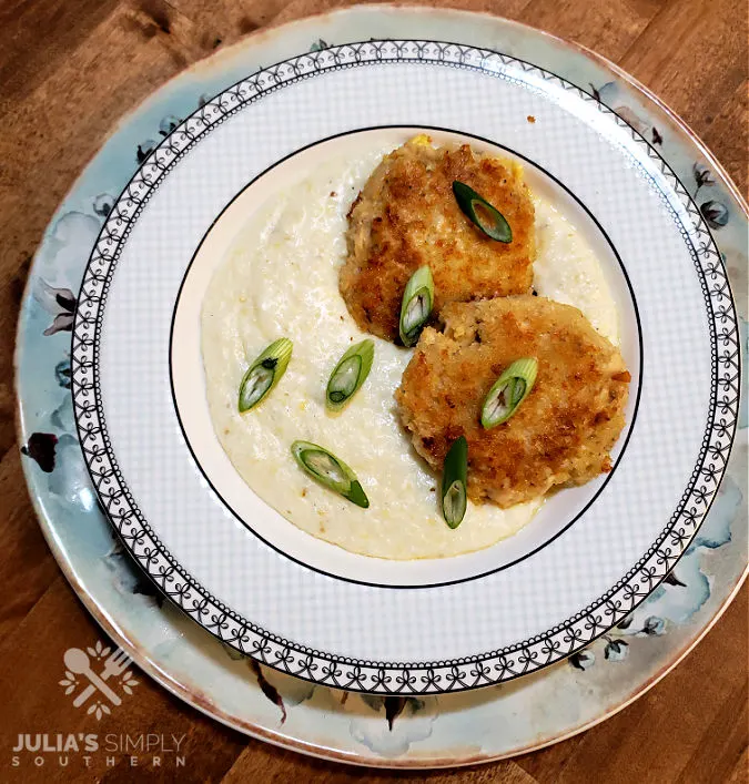 Bowl of creamy grits served with two salmon patties and garnished with spring onion