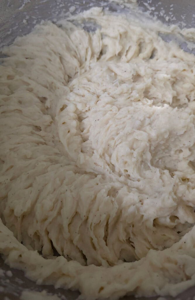 Whipping potatoes with an electric hand mixer until smooth and creamy