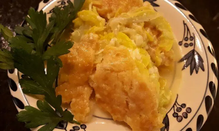 Southern style squash casserole on a plate garnished with vegetable greenery