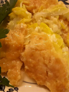 Southern style squash casserole on a plate garnished with vegetable greenery