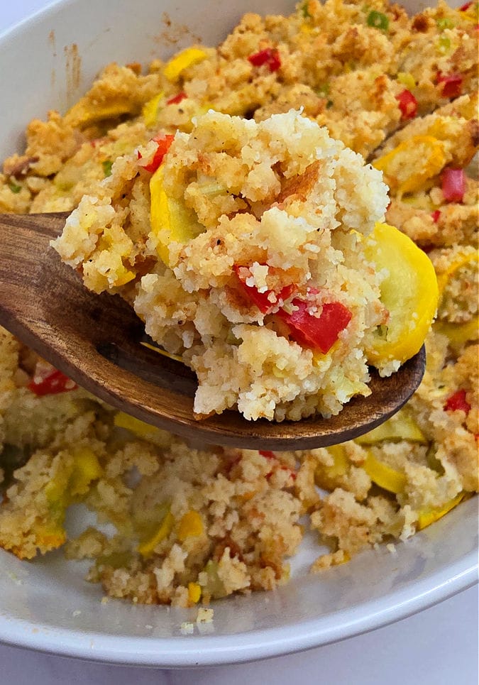 Serving spoon with a serving of yellow squash dressing casserole that highlight the ingredients
