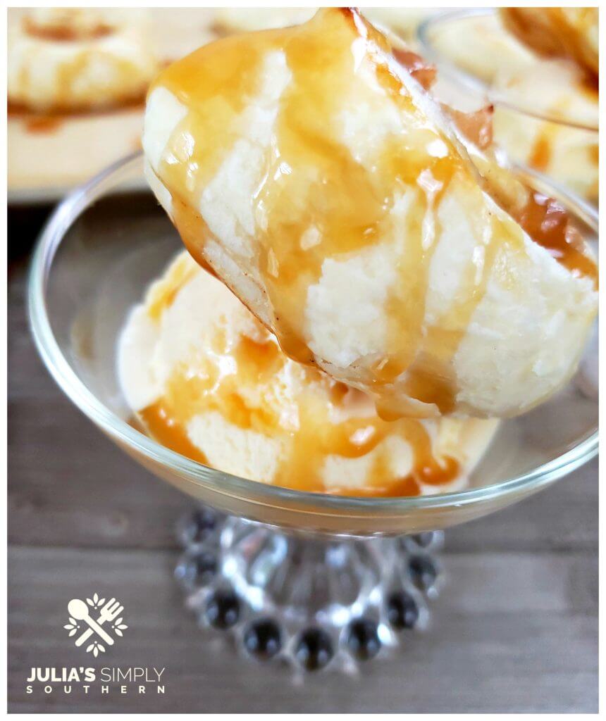 Glass serving dish with vanilla ice cream topped with an apple puff and caramel sauce
