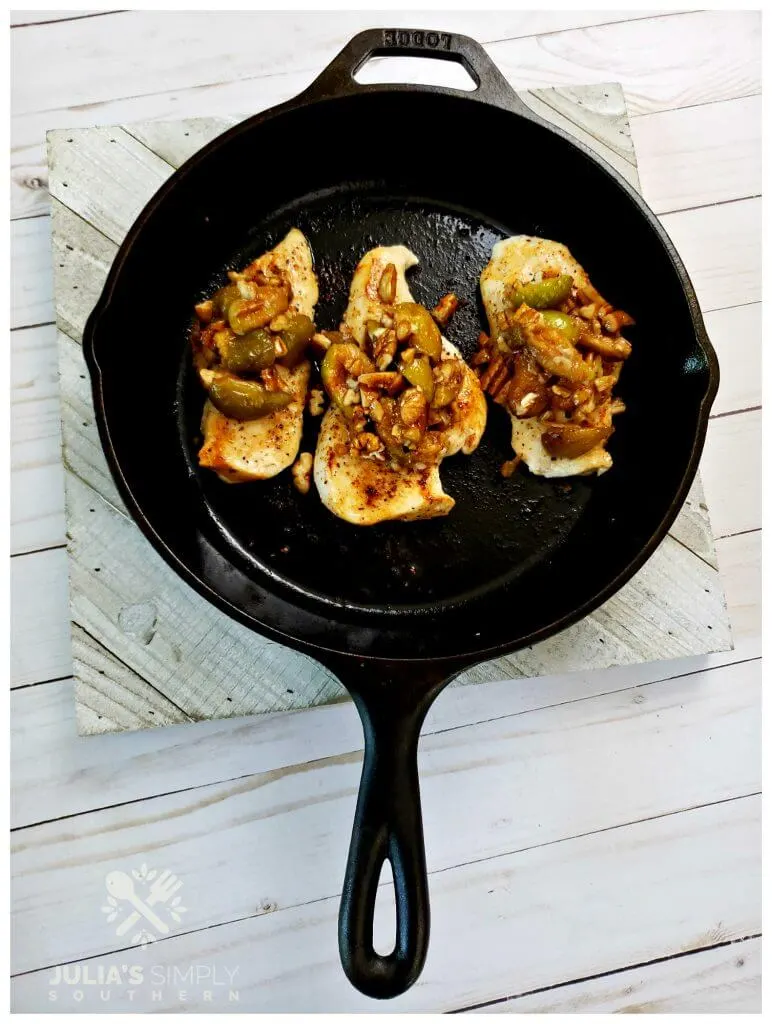 Chicken cooked in a cast iron skillet topped with fig and pecans