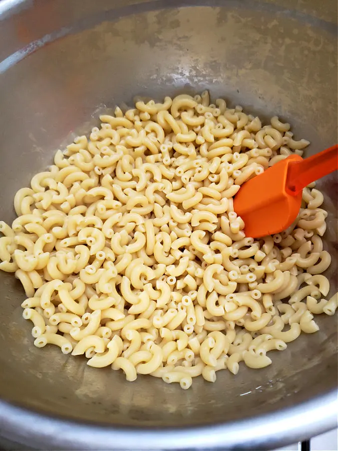 cooling cooked elbow macaroni in a chilled stainless mixing bowl