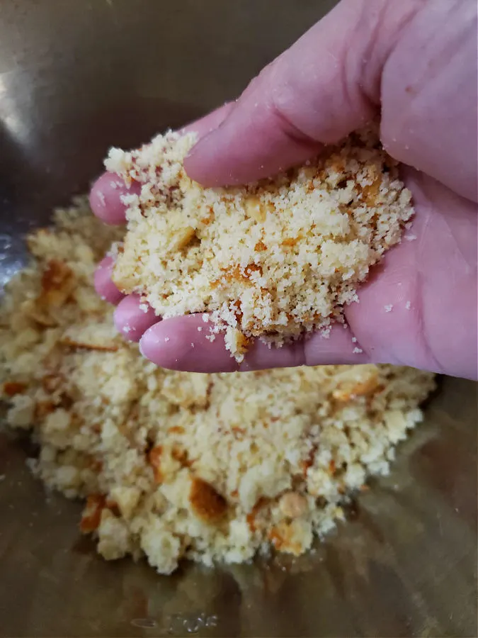 crumbling homemade cornbread into a mixing bowl to make dressing or stuffing