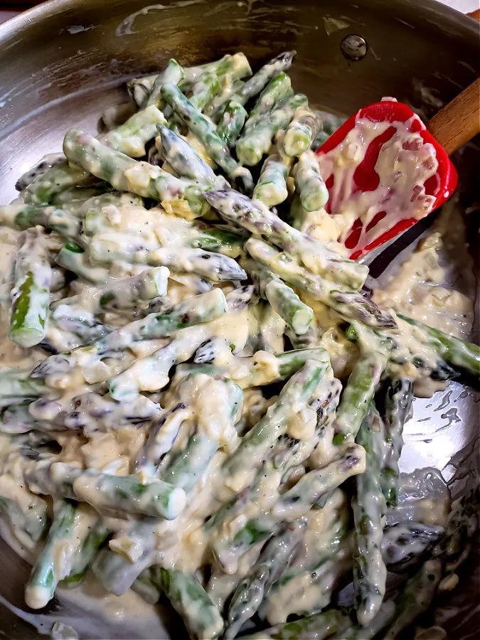 mixing cream of celery condensed soup with sautéed asparagus and onions with a spatula
