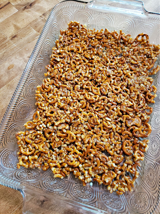 A rectangle glass baking dish with a bottom crust layer made with pretzels
