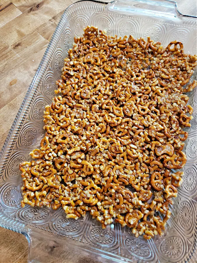 A rectangle glass baking dish with a bottom crust layer made with pretzels