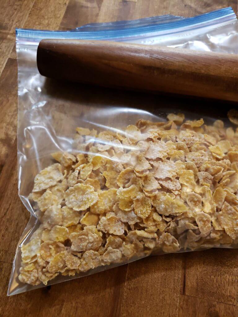Kellogg's frosted flakes in a plastic food storage bag with a rolling pin resting on top