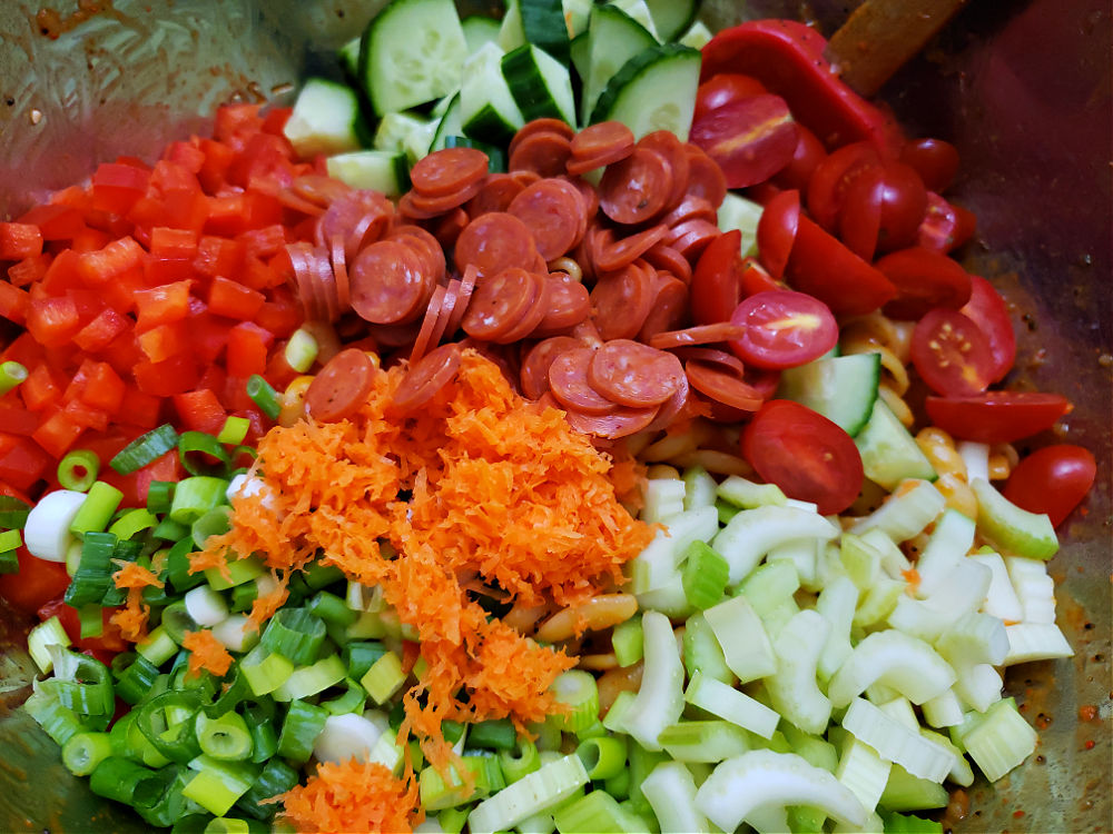 mixing bowl with cooked pasta and veggies for pasta salad mixing