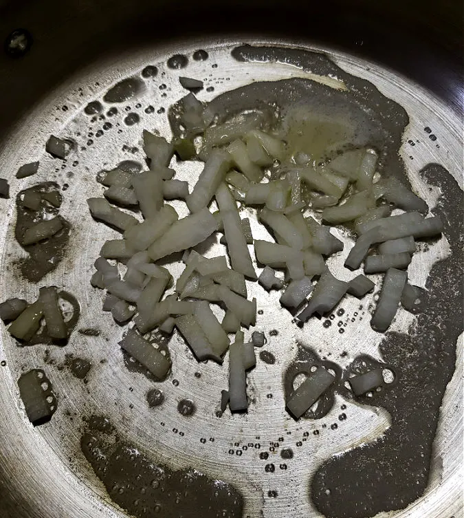 Sautéing diced onions in a large skillet on the stove top