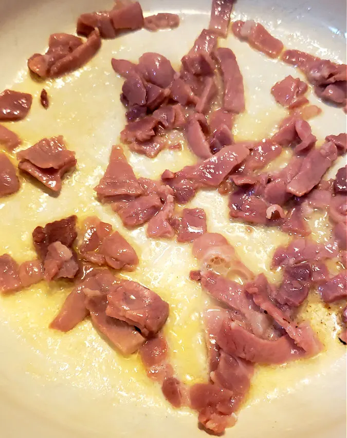 Sizzling country ham pieces in a dutch oven