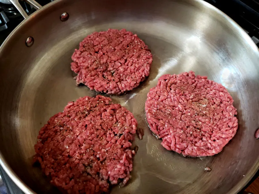 large skillet with ground beef patties frying
