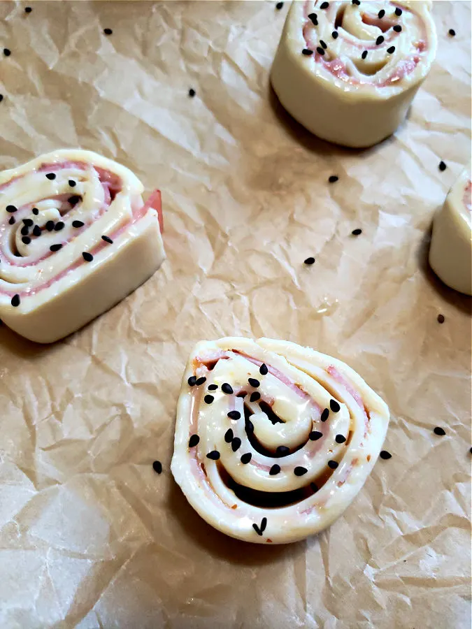 sprinkle black sesame seeds over pinwheels before baking