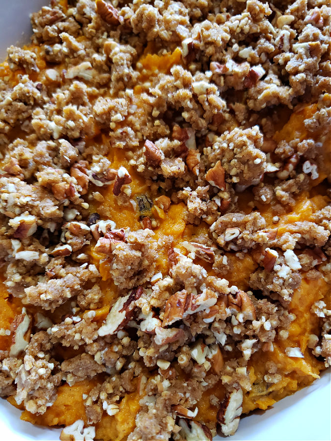 adding the crispy streusel topping to the sweet potato casserole before baking