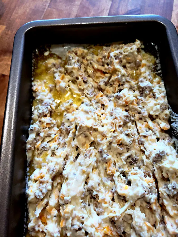 Sausage bread dough in melted butter in a loaf pan ready for baking